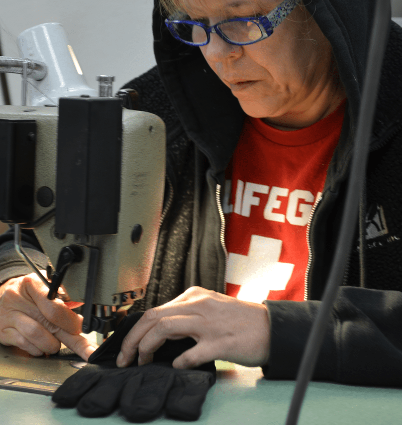 Employee Sewing a pair of gloves